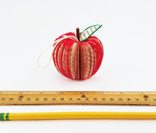 Load image into Gallery viewer, Handmade apple book ornament resting on table showing size (2.75&quot; in diameter)
