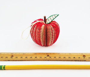 Handmade apple book ornament resting on table showing size (2.75" in diameter)